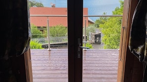 Une porte en bois donnant sur un lac, avec des bâtiments visibles au loin.