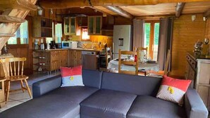 Un intérieur de chalet chaleureux avec un canapé d’angle, des meubles de rangement en bois et un coin cuisine.