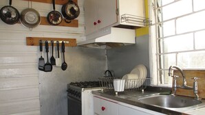 Una cocina con armarios blancos, una estufa, un fregadero y diversos utensilios colgados en la pared.