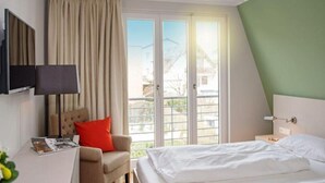 Een hotelkamer met een bed, een stoel, een bureau met lamp en een televisie.