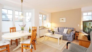 A well-lit living room with a dining area, a sofa, and a television. - Alte Stadtgärtnerei, Whg. 11 - Old city nursery (Sylt)