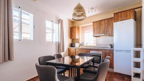 Une cuisine moderne avec des meubles en bois, un réfrigérateur blanc et une table à manger avec des chaises.