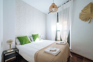 Une chambre à coucher bien rangée, avec un lit, des oreillers, une lampe de chevet et une feuille décorative accrochée au mur.