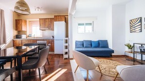 Une cuisine moderne avec des meubles en bois, un réfrigérateur blanc et un coin repas comprenant une table et des chaises.