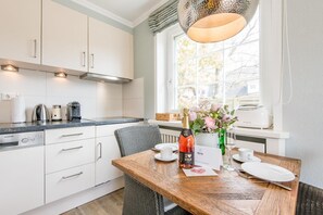 Eine moderne Küche mit weißen Schränken, einem Holzespeisetisch und einem Fenster mit Blick auf Bäume.