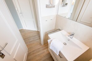 Ein modernes Badezimmer mit einem weißen Waschbecken, einem Handtuch und einem Spiegel.