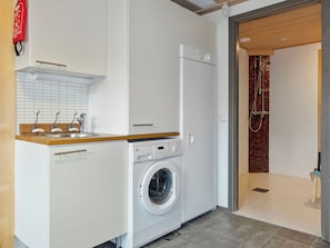 A compact laundry area with a washing machine, a sink, and a shower. - Pulkka 1 by Interhome (Salla)