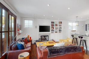 Relax in a cozy seating area with a leather sofa and armchair, featuring a flat-screen TV above a fireplace.