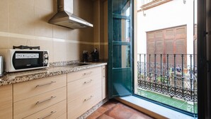 A kitchen with a microwave, cabinets, and a window overlooking a balcony. - Homey Seville. Bright Apartment in Santa Cruz (Sleeps 6; Parking Optional) (Sevilla)