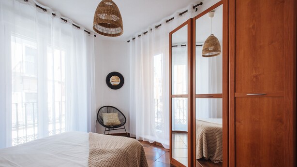 A bedroom with a bed, a chair, a wardrobe, and a large mirror. - Homey Seville. Bright Apartment in Santa Cruz (Sleeps 6; Parking Optional) (Sevilla)