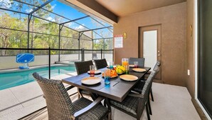 A covered outdoor dining area with a pool view, wicker chairs, and a table set with plates, glasses, and fruit. - 

PerfectVacationHome5/4 Sleep12close to DisneyWorld, great forfamily gathering  (Kissimmee)