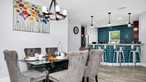 A modern kitchen with a teal backsplash, a dining area with grey upholstered chairs, and a bar area with white stools. - 

PerfectVacationHome5/4 Sleep12close to DisneyWorld, great forfamily gathering  (Kissimmee)