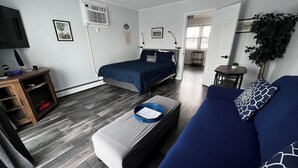 Une chambre moderne avec un lit, un canapé, une télévision et une petite table.