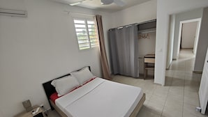 A bedroom with a bed, bedside table, and a desk with a chair. - Sunbeam Bottom of villa T3 beach 2km away  (Sainte-Anne)