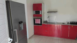 A compact kitchen with a refrigerator, microwave, oven, and sink. - Sunbeam Bottom of villa T3 beach 2km away  (Sainte-Anne)
