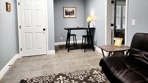 A living room with a brown leather couch, a small table with a lamp, and a door. - Lovely One Bedroom Home (Lakeland)