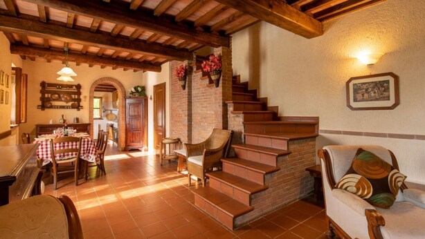 A rustic interior with a dining area, staircase, and seating.