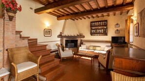A cozy living room with a fireplace, wicker furniture, and a television.