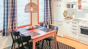 Una cucina compatta con tavolo e sedie, forno a microonde e piano cottura.