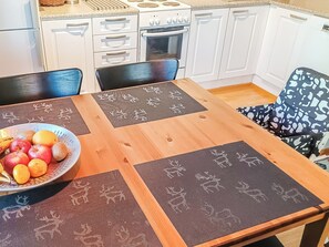 Un coin repas avec une table en bois, des sets de table ornés de motifs animaliers et un saladier rempli de fruits.