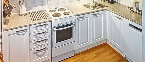 Une cuisine de taille réduite avec des meubles blancs, un four à micro-ondes, une cuisinière et un évier.