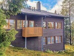 Et moderne træhus med store vinduer og en balkon.