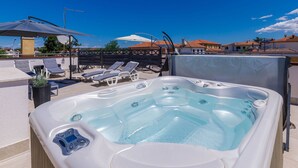Ein Poolbereich auf dem Dach mit Whirlpool, Liegestühlen und Sonnenschirmen.