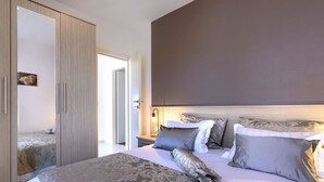 Ein Schlafzimmer mit einem großen Bett, einem Kleiderschrank und einem Nachttisch mit einer Lampe.