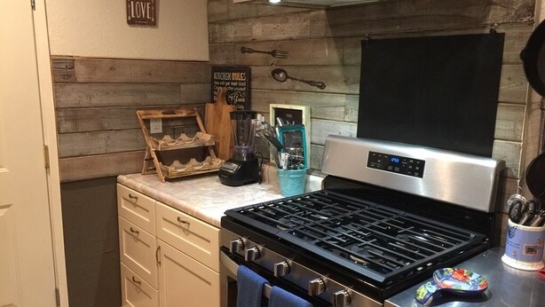 Eine Küche mit einem Edelstahlherd, Holzvertäfelung und einem Schild mit der Aufschrift 'Kitchen Rules'.