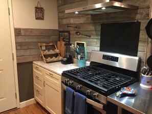A kitchen with a stainless steel stove, wooden wall paneling, and a sign that reads "Kitchen Rules." - Furnished Housing (Lakeport)
