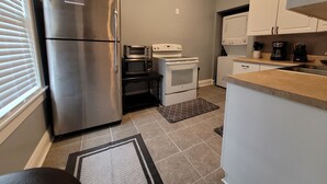 A compact kitchen with a stainless steel refrigerator, a microwave, an oven, and a coffee maker.