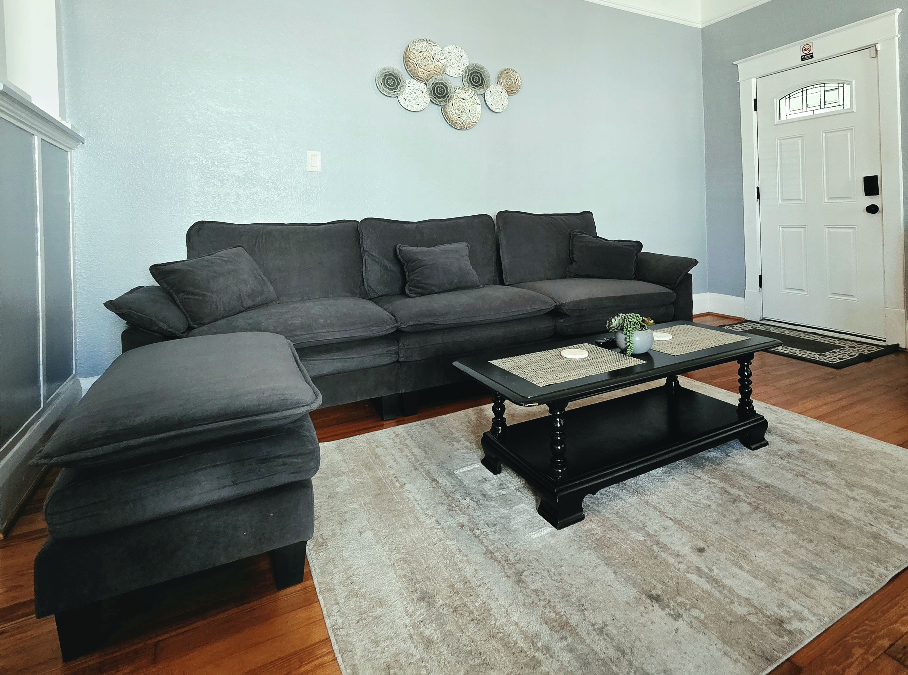 A living room with a sectional sofa, a coffee table, and a decorative wall piece.