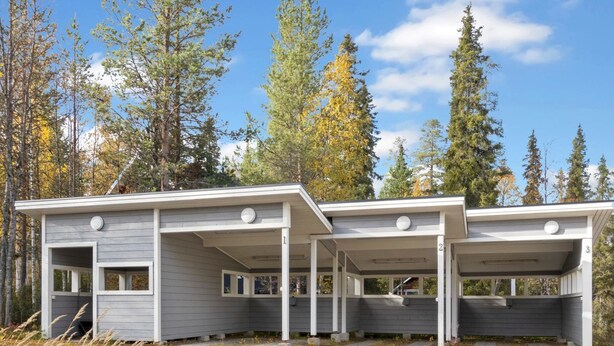 A modern cabin with a covered porch and a garage, surrounded by tall trees and a clear sky. - Pulkka 2 by Interhome (Salla)