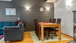 A cozy living room with a grey sofa, a wooden dining table with chairs, and a clock on the wall. - Pulkka 2 by Interhome (Salla)