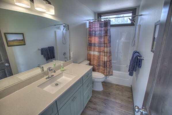 A bathroom with a sink, mirror, toilet, and shower.