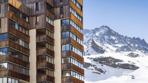Un hôtel à plusieurs étages au design moderne, doté de balcons et de grandes fenêtres.