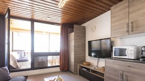 Une chambre d’hôtel moderne avec un plafond en bois, une grande fenêtre, un téléviseur à écran plat, un four à micro-ondes et un canapé.