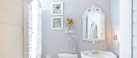 Un baño con inodoro, lavamanos y zona de ducha.
