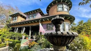 A Victorian-style house with a prominent turret and a fountain in the garden. - Pinschower Inn (Cloverdale)