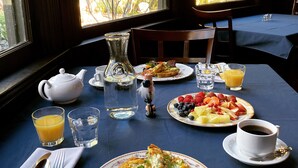 A breakfast table with plates of food, glasses of orange juice, and a teapot. - Pinschower Inn (Cloverdale)