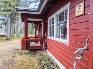 A red wooden house with a porch, a number 7 sign, and a forested background.