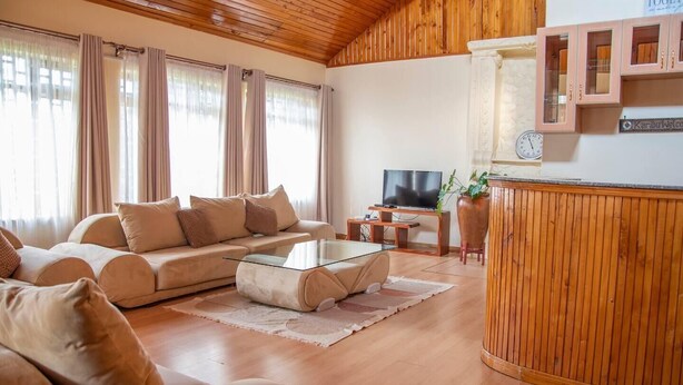 Un salon chaleureux avec un canapé, une table basse, un téléviseur et un lambris en bois.