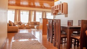 Un salon spacieux avec un plafond en bois, un coin repas comprenant une table et des chaises en bois, et un ensemble de canapés.