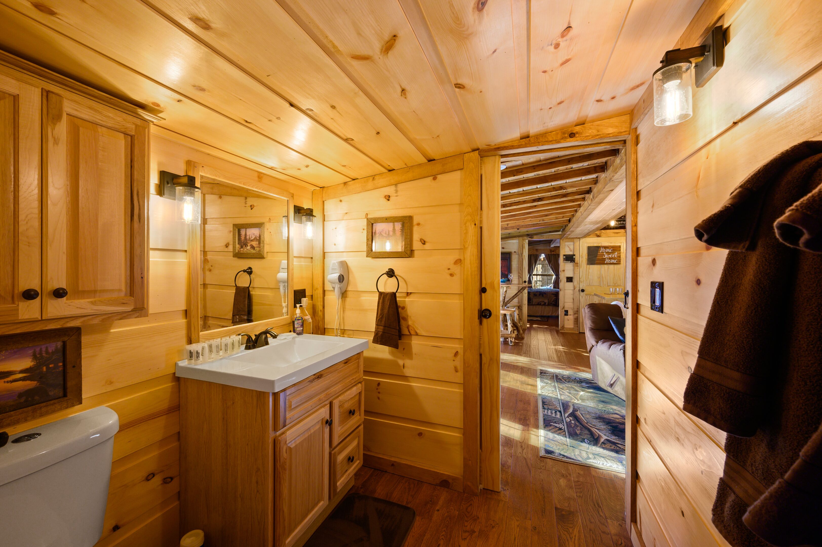 Un intérieur en bois comprenant une salle de bain, des murs en bois, un lavabo, un miroir et une serviette accrochée au mur.