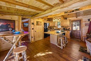 A rustic wooden interior with a central island, wooden bar stools, and a kitchen area with appliances.