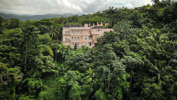 Un grand immeuble à étages, entouré d’une végétation tropicale luxuriante.