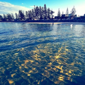 A clear lake with visible underwater rocks and reflections.