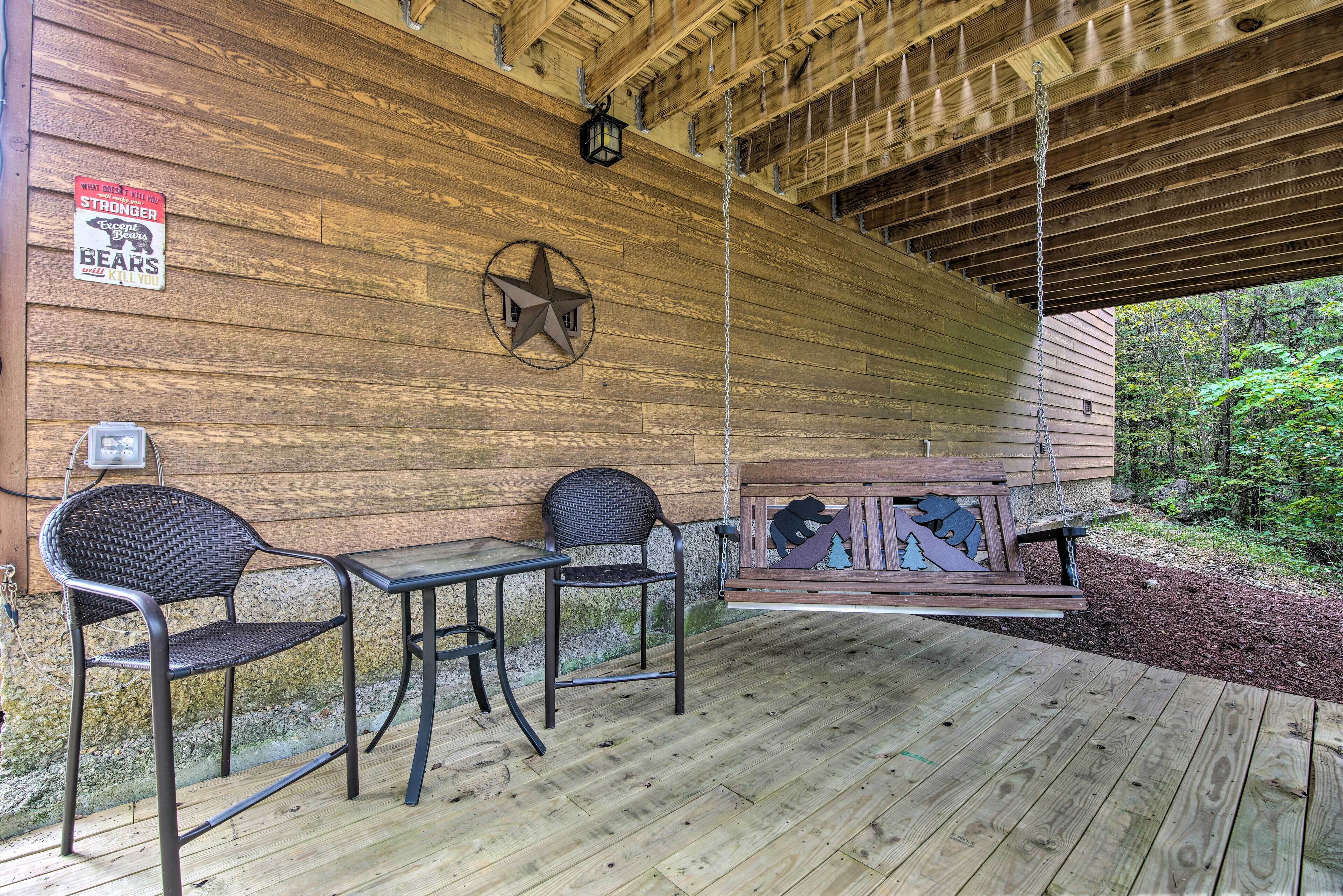 A wooden deck with metal chairs and a table, a star decoration, and a bear cutout on a bench.