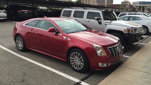 A red Cadillac parked in a multi-level parking garage with a visible structure overhead. - Luxury Condo downtown Lansing (Lansing)