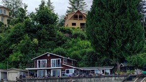 Een pand aan het water met een groot huis, een steiger en een klein gebouwtje.